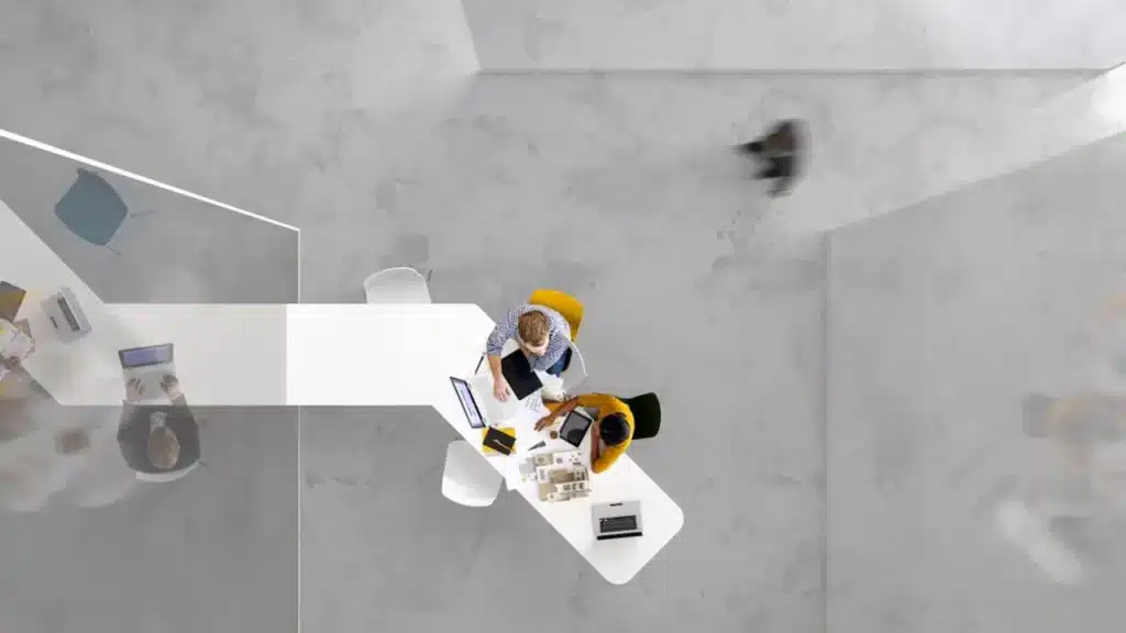 hand partner operating partner : vue de haut de deux personnes qui travaillent sur un bureau blanc